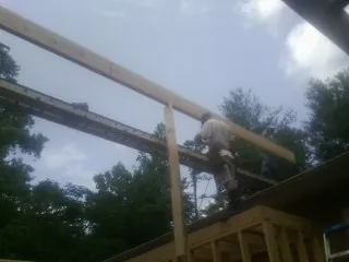 Carpenter setting a ridge beam over a new addition frame — Ice Dam Removal by Roofing Brothers in Hematite