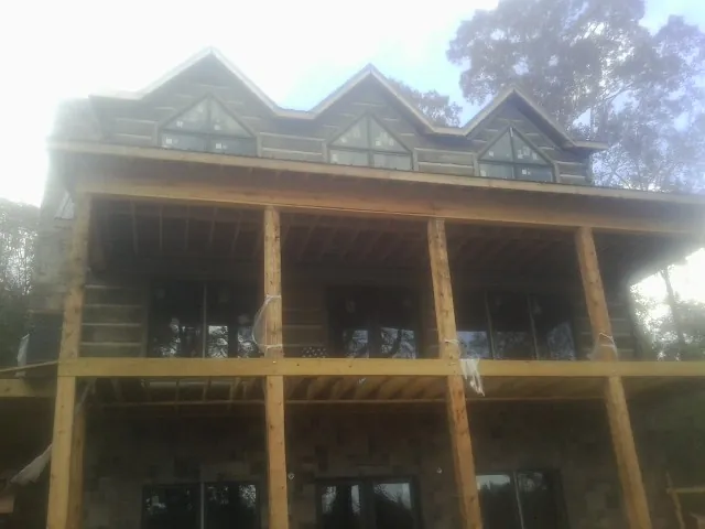 Dormers and porch framing on a large log home under construction — Roof Coating work by our crew in Hematite