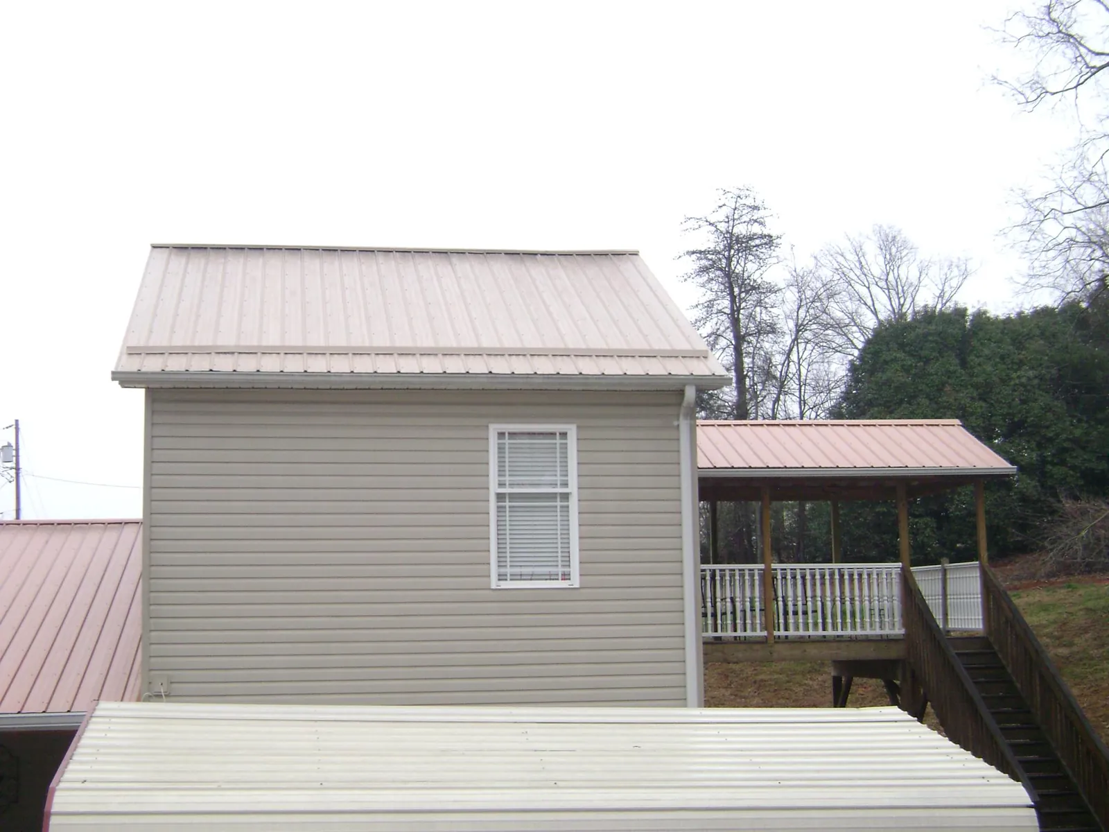 Tan metal roofs on a two story addition and attached porch, from a Roof Replacement job in Hematite